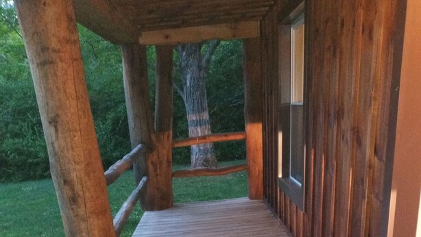 Une terrasse en bois mène à un bâtiment au style rustique, entouré de verdure.