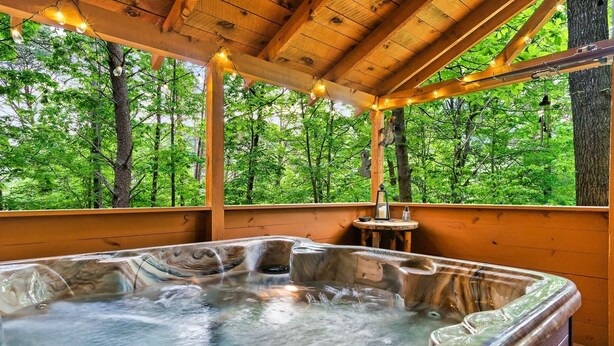 Un bain à remous dans un chalet en bois avec vue sur la forêt.