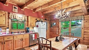 L’intérieur d’un chalet en bois rustique comprend une cuisine, un coin repas et de grandes fenêtres.