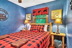 A bedroom with a checkered bedspread, a headboard with a bear-themed valance, two bedside lamps, and a clock. - Summer Specials! Cozy Cabin, ADA, HotTub, Easy Drive, 3Bdm+Nook, Family Retreat (Sevierville)
