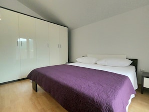A bedroom with a bed, a wardrobe, and a nightstand.