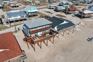 Una casa frente al mar con terraza de madera, varias habitaciones y vista a la playa.