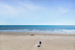Una playa con una única silla azul y una vista despejada del océano.