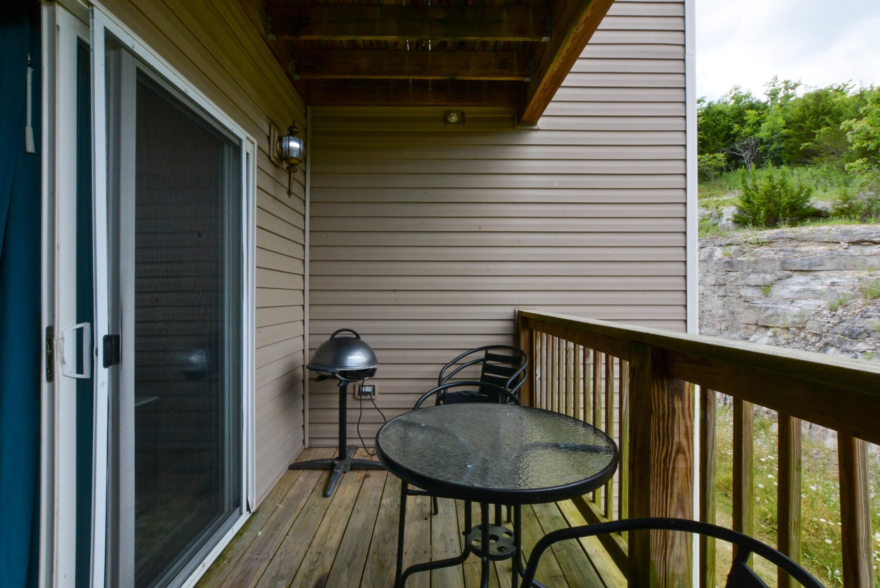 A covered outdoor area with a sliding glass door, a small table with chairs, and a lamp.