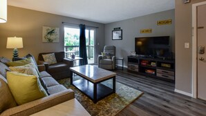 Un salon comprenant un canapé, un fauteuil, une table basse, un téléviseur et une cheminée.
