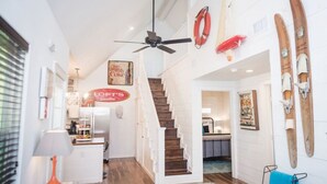 A spacious interior with a staircase leading to an upper level, a ceiling fan, and a kitchen area.