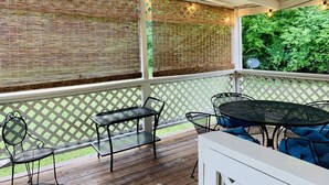 A covered patio with a wooden deck, metal furniture, and a lattice wall with string lights. - Cozy, Country Cottage close to Oaklawn, near Bypass (Hot Springs)