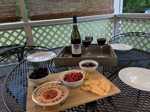 Une table dressée avec une bouteille de vin, des verres, des bols remplis de fruits rouges et une planche en bois sur laquelle sont disposés divers amuse-gueules.
