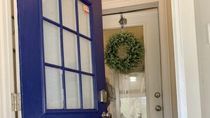 A blue door with a frosted glass panel, a doormat, and a wreath on the adjacent door. - Cozy, Country Cottage close to Oaklawn, near Bypass (Hot Springs)