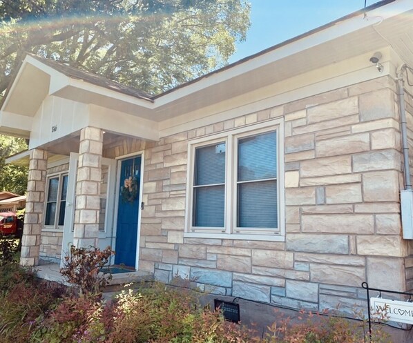 Une maison en pierre avec une porte bleue et deux fenêtres.