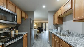 A modern kitchen with wooden cabinets, granite countertops, stainless steel appliances, and a central island. - GoodVibes Hillside (Branson)