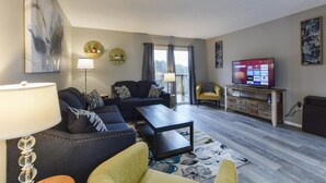 A modern living room with a sofa set, a coffee table, a TV, and a lamp. - GoodVibes Hillside (Branson)