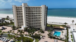 A multi-story hotel with a pool, beach view, and parking area. - Gulf Coast / Direct Beachfront View - Steps to Sand & Sunset (Fort Myers Beach)