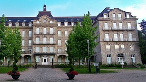 A large, historic building with a symmetrical facade, multiple balconies, and a central entrance.