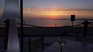 A beachside table with a glass of wine, overlooking the ocean at sunset.