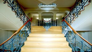 A grand staircase with ornate metal railings and wooden steps leading to an upper floor.