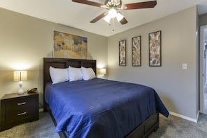 A bedroom with a large bed, two bedside tables, a ceiling fan, and three framed artworks on the wall. - Whimsy Vibes (Branson)