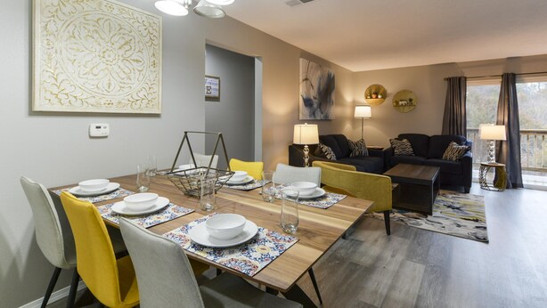 En matplats med ett träbord som är dukat för fyra personer, en soffa och en lampa.