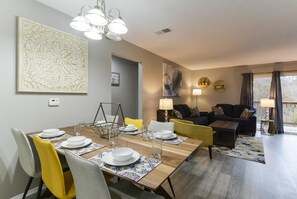 A dining area with a wooden table set for four, a sofa, and a lamp. - Whimsy Vibes (Branson)