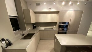 Una cucina moderna con elettrodomestici integrati, un'isola centrale e un'area pranzo con sgabelli.