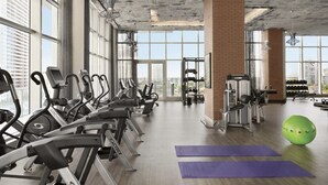 Una palestra con macchinari cardio, attrezzatura per sollevamento pesi e tappetini da yoga.