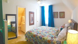 A bedroom with a bed, a bedside lamp, a mirror, and a door leading to a bathroom. - Upscale And Urban In The City (Columbia)