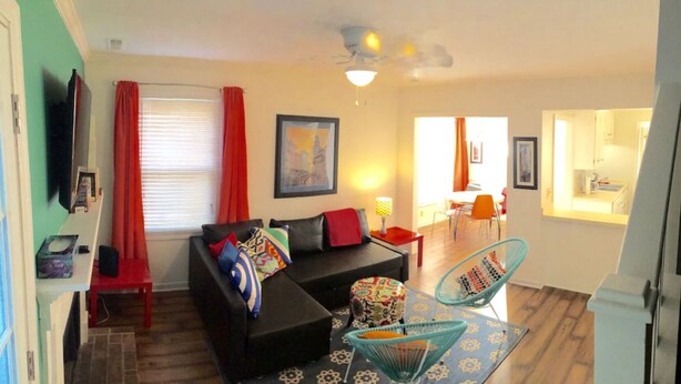 A living room with a sofa, a coffee table, and a chair. There is a dining area with a table and chairs. - Upscale And Urban In The City (Columbia)