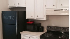 A kitchen with white cabinets, a black refrigerator, a microwave, and a stove. - Upscale And Urban In The City (Columbia)