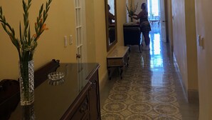 A hallway with a chandelier, a mirror, a vase with flowers, and a patterned floor. - Villa Avana (Havana)