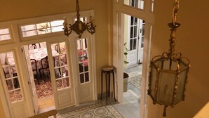 A staircase with a white railing leading to a room with a patterned floor and a chandelier. - Villa Avana (Havana)