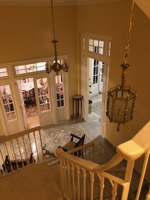 A staircase with a white railing leading to a room with a patterned floor and a chandelier. - Villa Avana (Havana)
