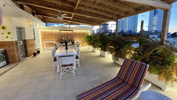 An outdoor patio with a wooden ceiling, a dining table with chairs, and potted plants. - Villa Avana (Havana)