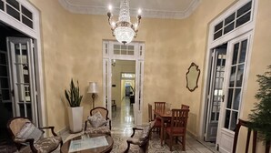 A spacious room with a chandelier, a dining area with wooden chairs and a table, and a large potted plant. - Villa Avana (Havana)