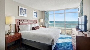 Camera d'hotel con un letto grande, una TV, una scrivania e vista sull'oceano.