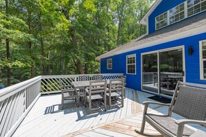 A blue house with a deck, outdoor furniture, and a forested background. - Lake Gaston Lyons creek 3 bedroom plus bunkbed loft 2 bathroom sleeps 10-12 (Macon)