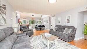 Ein geräumiges Wohnzimmer mit grauen Sofas, einem Holztisch und einem gemusterten Teppich.
