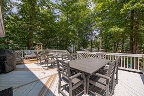A wooden deck with a table and chairs, surrounded by trees. - Lake Gaston Lyons creek 3 bedroom plus bunkbed loft 2 bathroom sleeps 10-12 (Macon)