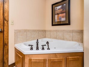 A bathroom with a freestanding bathtub, wooden cabinets, and a tiled backsplash. - Bear Hug (Reeds Spring)