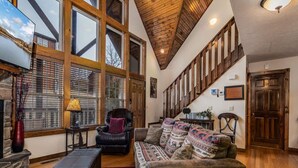 A spacious living room with a high ceiling, large windows, a fireplace, and a cozy seating area. - Bear Hug (Reeds Spring)