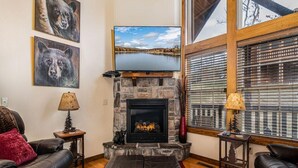 A cozy living room with a stone fireplace, leather sofas, and artwork on the walls. - Bear Hug (Reeds Spring)