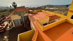 Ein gelbes Gebäude mit rotem Ziegeldach, einer Wendeltreppe und Blick auf die umliegende Landschaft.