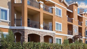 Un hotel de varios pisos con balcones, arcos de piedra y un cielo azul despejado.