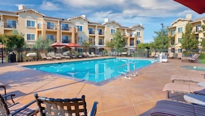 A pool area with lounge chairs and umbrellas, surrounded by multi-story buildings with balconies. - Napa Valley prime resort (Napa)