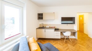 A modern kitchen with a built-in sink, a dining area with a white chair, and a sofa with cushions.