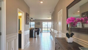A spacious hallway with a kitchen area, a dining area, and a large window providing natural light. - Exceptional Villa: Saltwater Pool, No Rear Neighbors, Game Room & Movie Theater (Davenport)