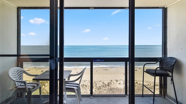 A balcony with a view of the beach, two chairs, and a table. - Direct Oceanfront condo- AMAZING VIEWS & GREAT AMENITIES! (Ocean City)