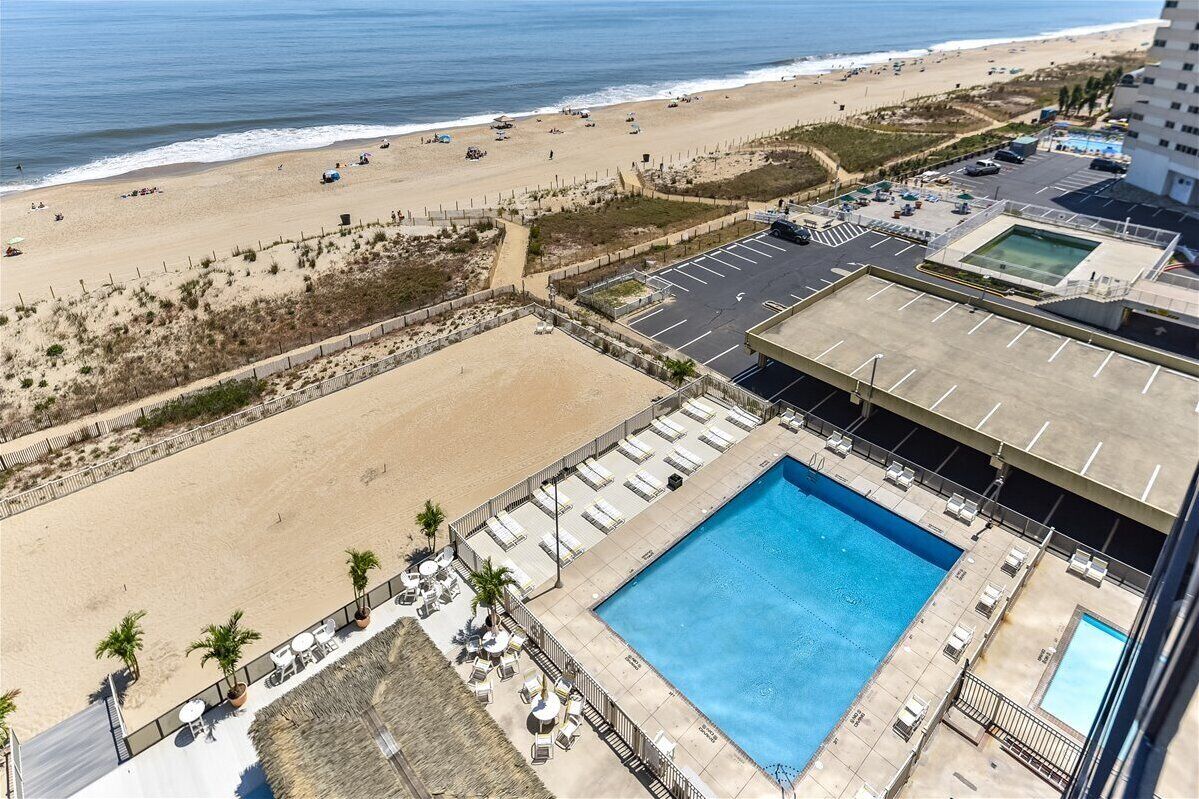 A hotel with a pool, beach view, and parking area.