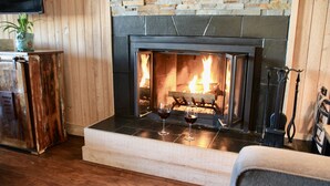 Una chimenea con dos copas de vino tinto, una pared de piedra y paneles de madera.