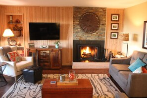 Una sala de estar con chimenea, televisor montado en la pared y un sofá.