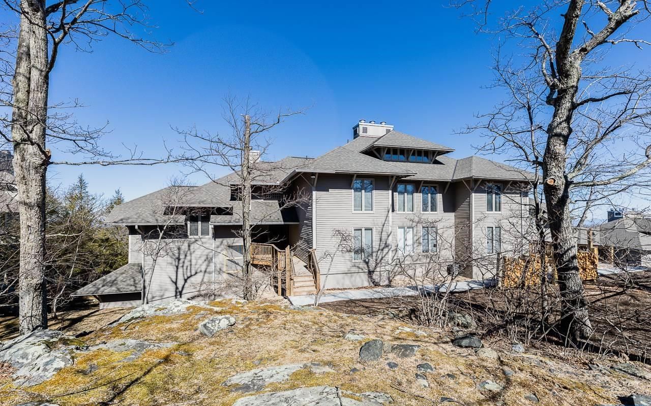 A two-story house with a stone foundation, a large front porch, and a chimney.